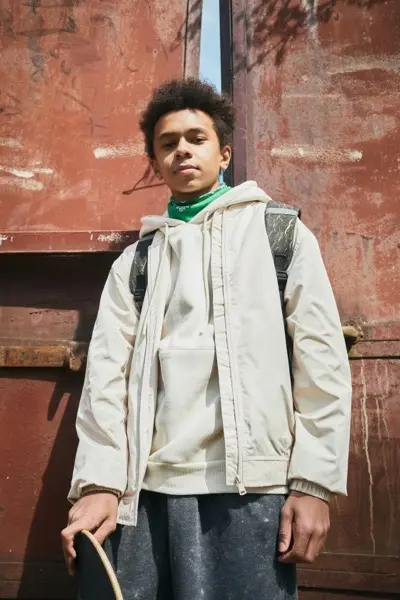 Portrait of African teenage boy with backpack looking at camera posing against the gates outdoors